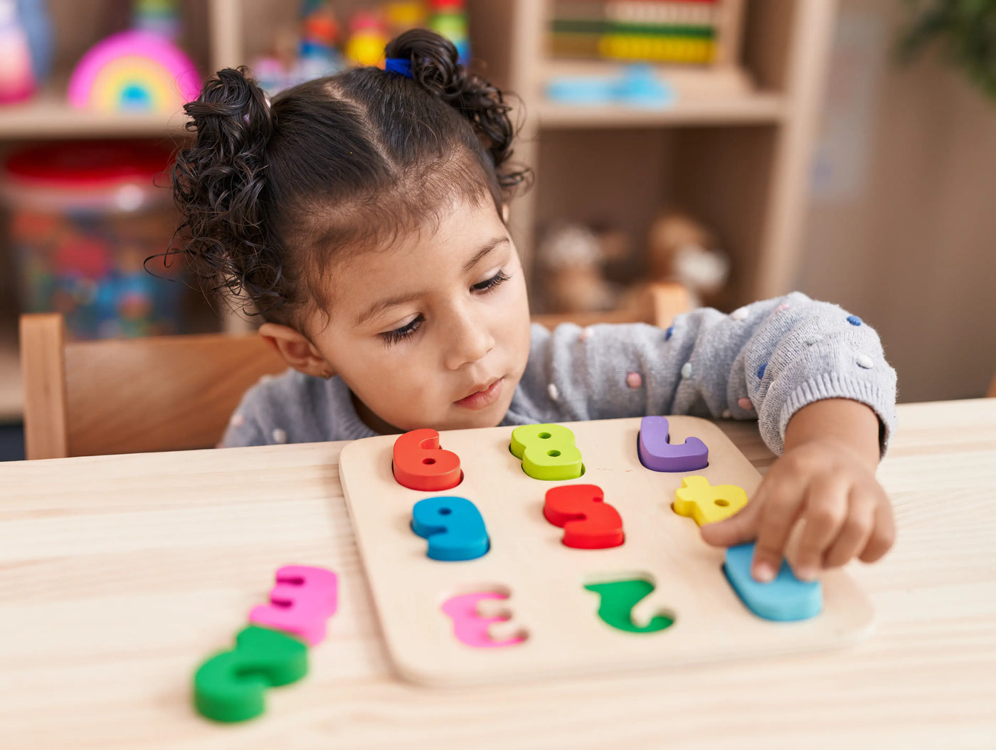 adorable-girl-playing-with-maths-puzzle-game-sitting-table-kindergarten